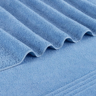 A close-up of blue bath towel with a folded corner showing the soft, textured fabric.