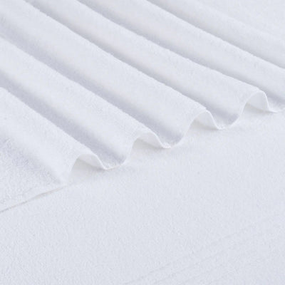 A close-up of white textured bath towel fabric with soft folds