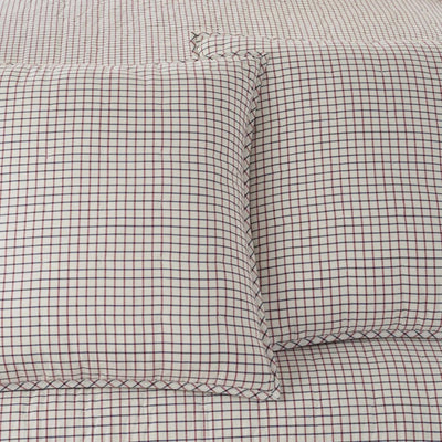 Close-up of a quilt with two matching euros in a small brown and off-white gingham check pattern.