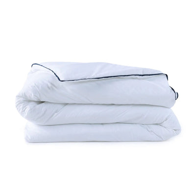 A folded white comforter with a thin dark blue piping trim, stacked neatly on a solid white background.