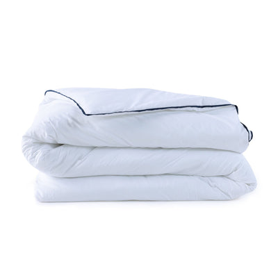 Folded white comforter with black piping on a white background