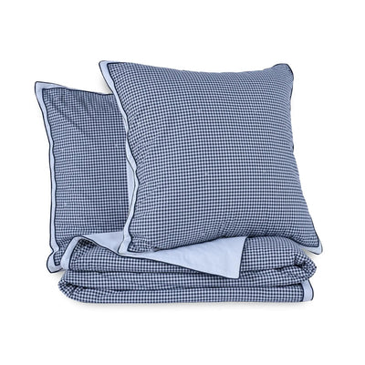 A folded quilt featuring a navy and white gingham checkered pattern, including two euros.