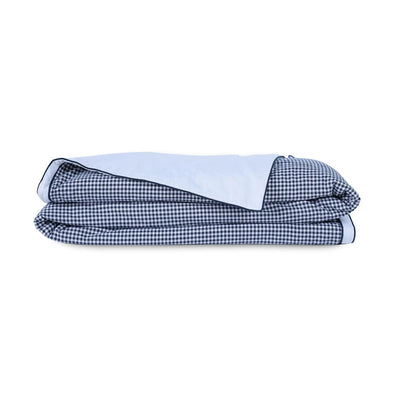 A folded quilt with a navy and white gingham checkered pattern on one side and a solid white reverse side, shown on a plain white background.