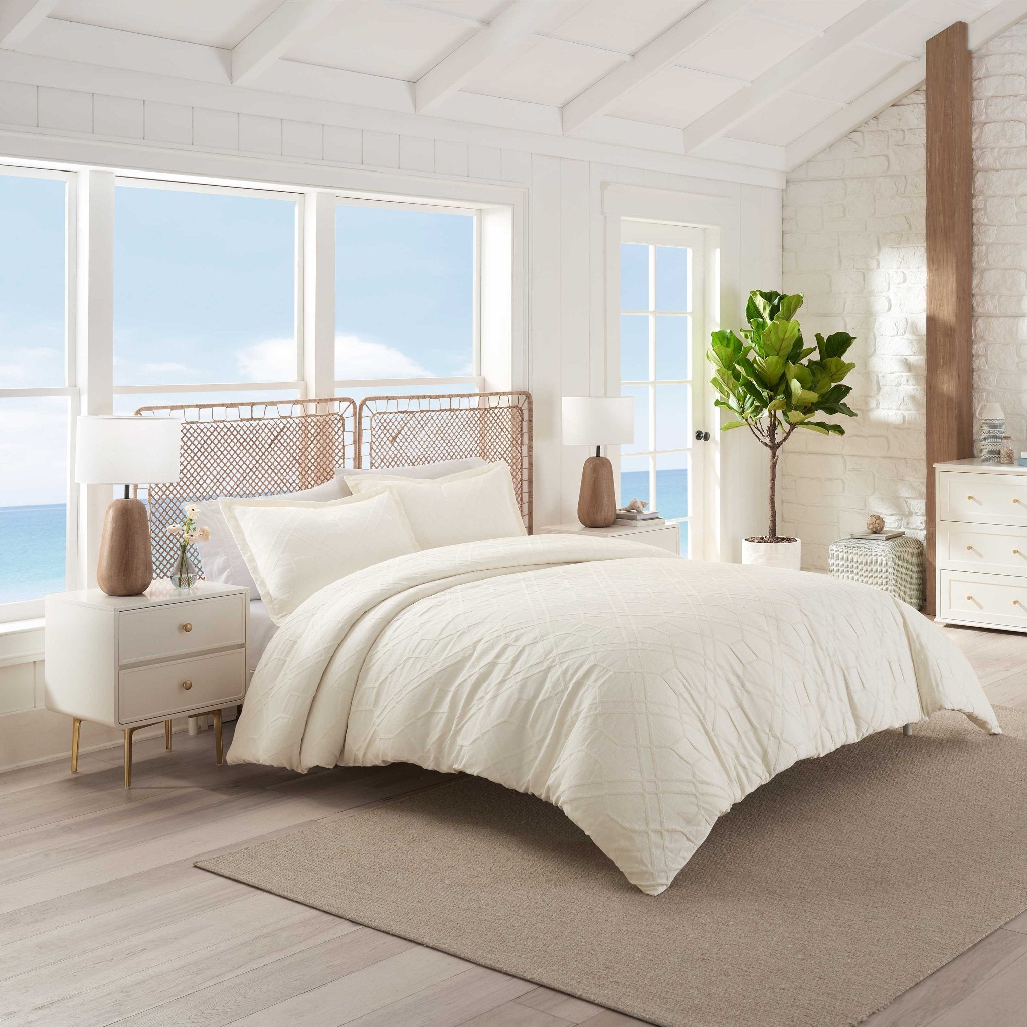 Neatly made bed with ivory comforter set in a bright bedroom.