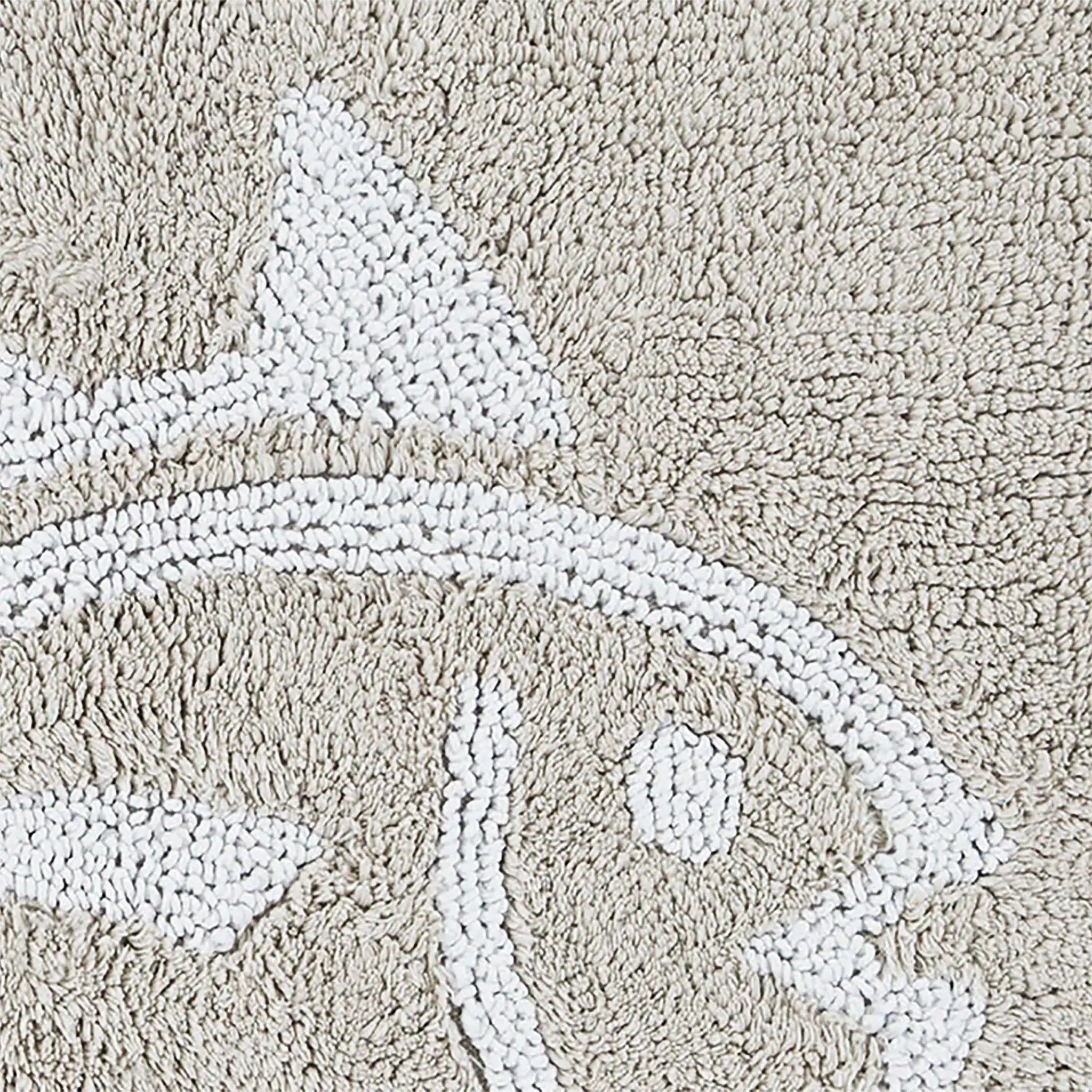 Close-up of a sand bath rug with a raised white abstract fish design.