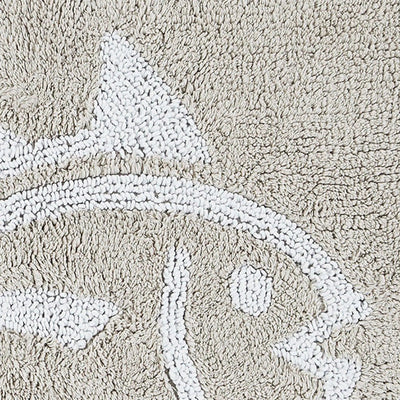 Close-up of a sand bath rug with a raised white abstract fish design.