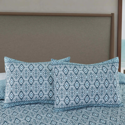 Blue patterned comforter set with two matching pillow shams displayed on a bed.