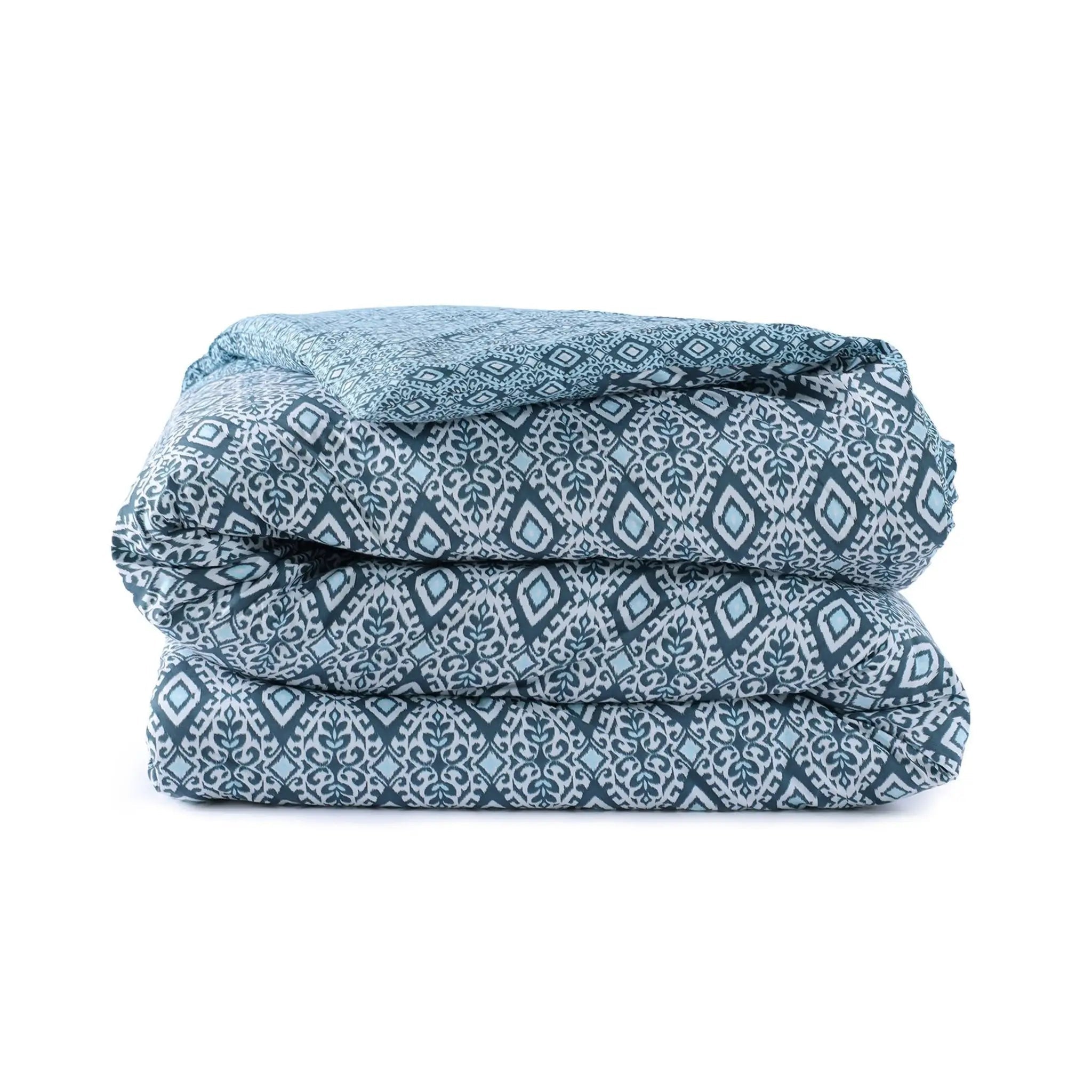 Folded blue patterned comforter on a white background