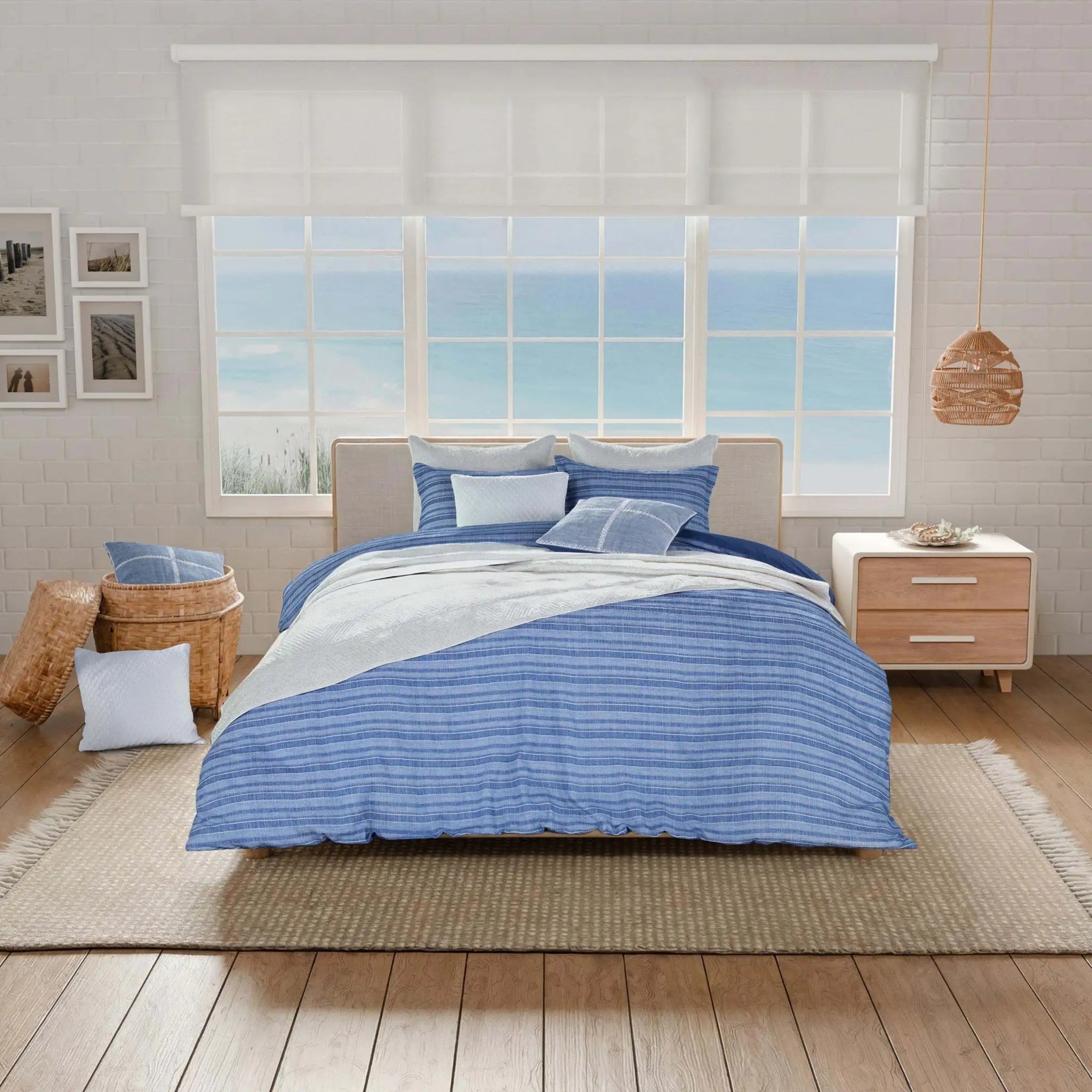 Bedroom with blue and white striped bedding, wooden nightstands, and a large window.