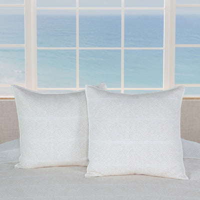 Two white pillows on a bed with a window in the background