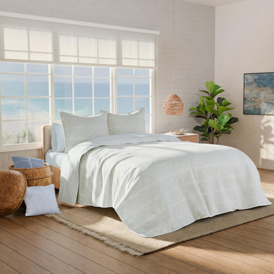 Neatly made bed with white bedding in a bright bedroom.