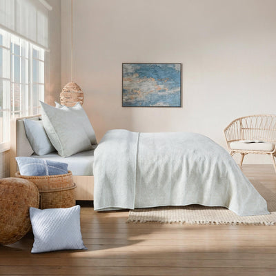 Neatly made bed with light-colored bedding in a bright bedroom.