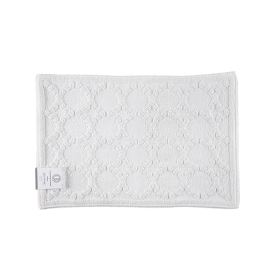 White bath rug with a textured circular pattern and a label on one corner.