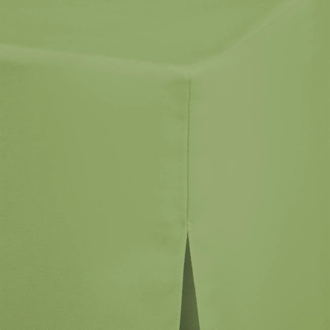 A close-up of a pistachio color fabric, showing the texture and a folded corner seam.