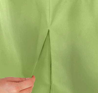 A close-up of a pistachio color table cover, showing a central seam and a hand pulling the fabric apart to demonstrate its stretch.