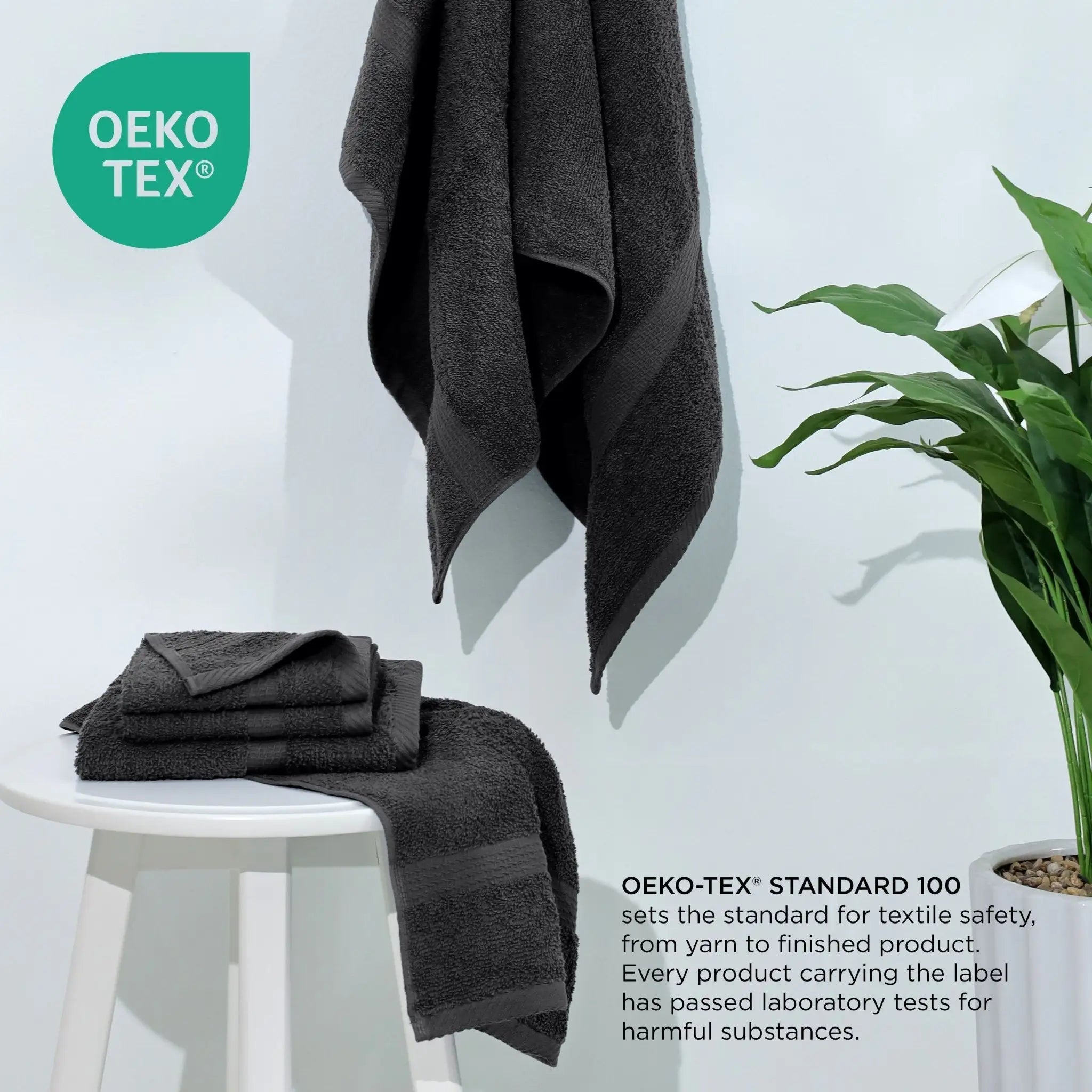 Black towels on a white stool with a plant, featuring the Oeko-Tex logo.