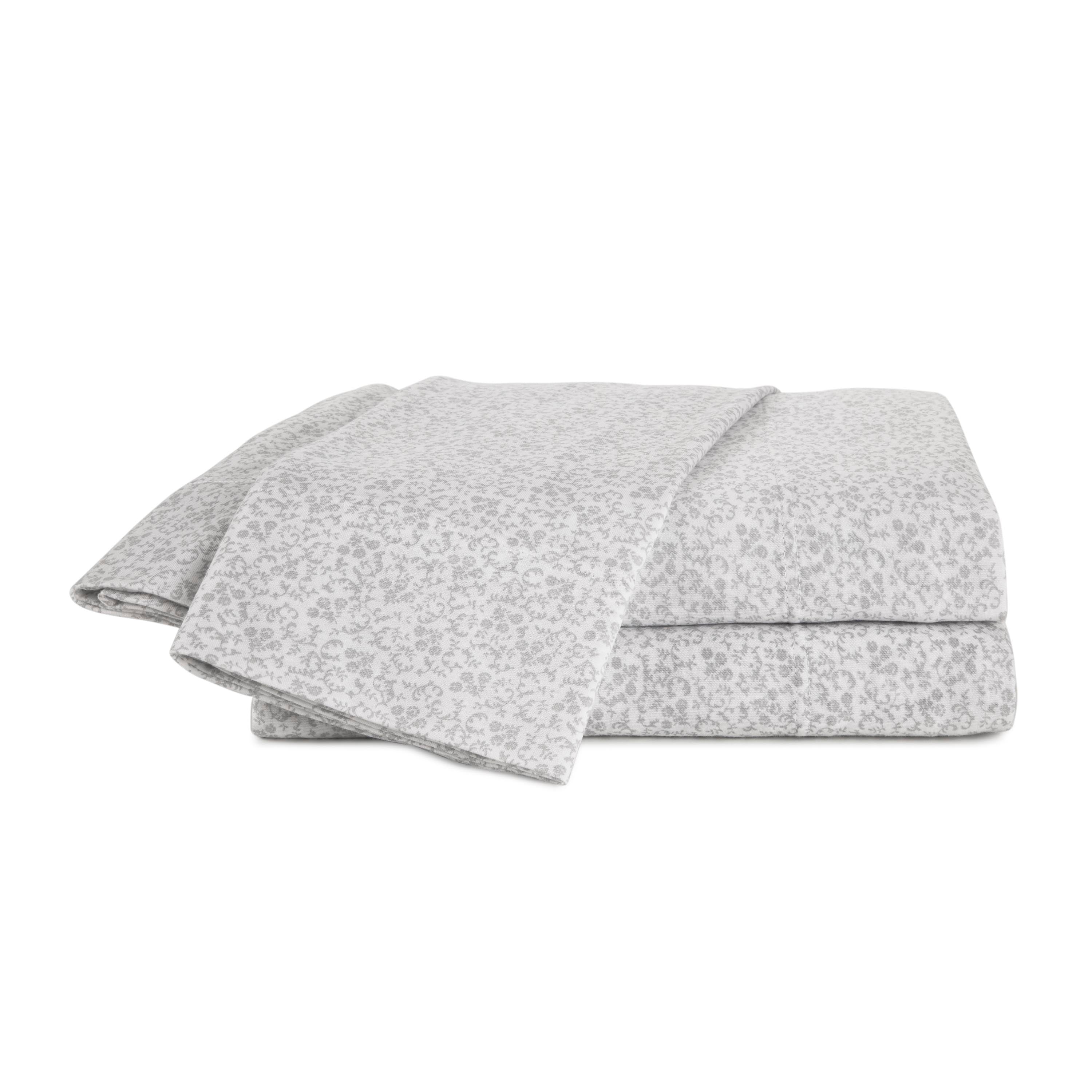 Soft grey sheet set with a subtle floral pattern, neatly folded and stacked.