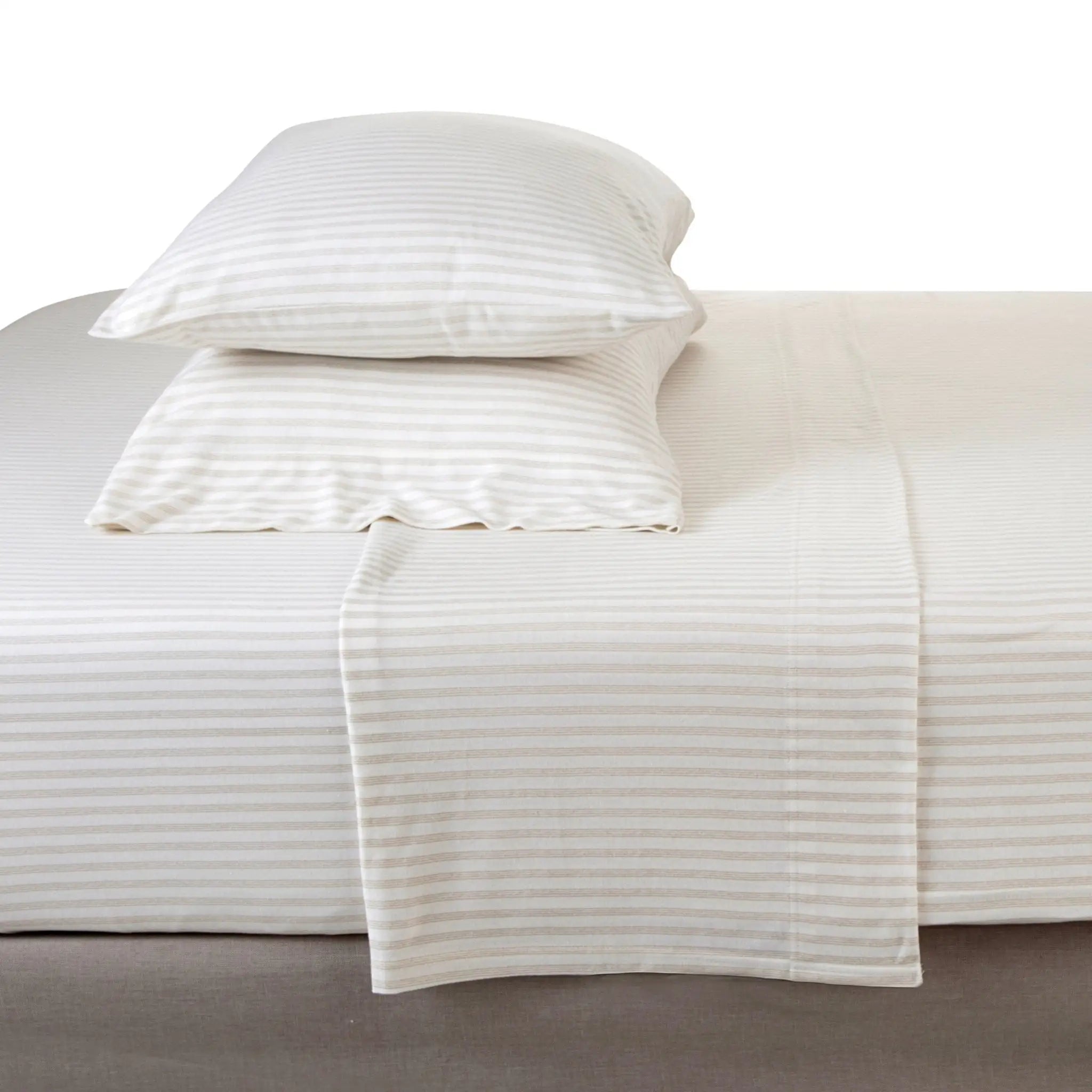 A bed dressed in white and beige horizontally striped bedding, featuring a fitted sheet, two matching pillowcases, and a folded top sheet draped over the edge, set against a plain white background.