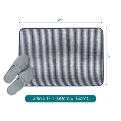 A rectangular black bath rug shown on a white background with dimension arrows indicating 24 inches by 17 inches, plus a pair of gray slippers placed on the mat. A teal label at the bottom reads 24in x 17in (60cm x 43cm).