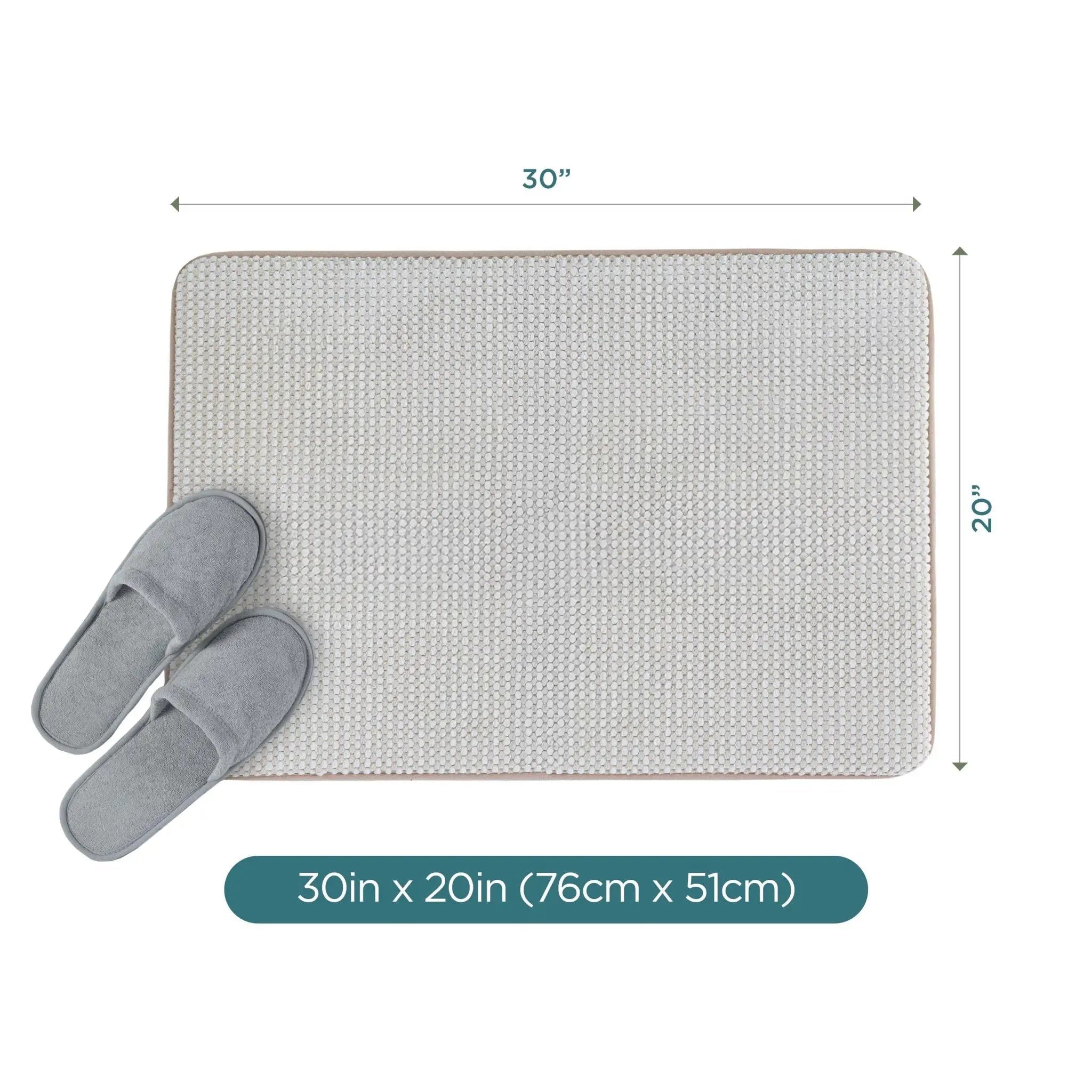 A rectangular sand bath rug shown on a white background with dimension arrows indicating 30 inches by 20 inches, plus a pair of gray slippers placed on the mat and a teal label at the bottom reading 30in x 20in (76cm x 51cm).