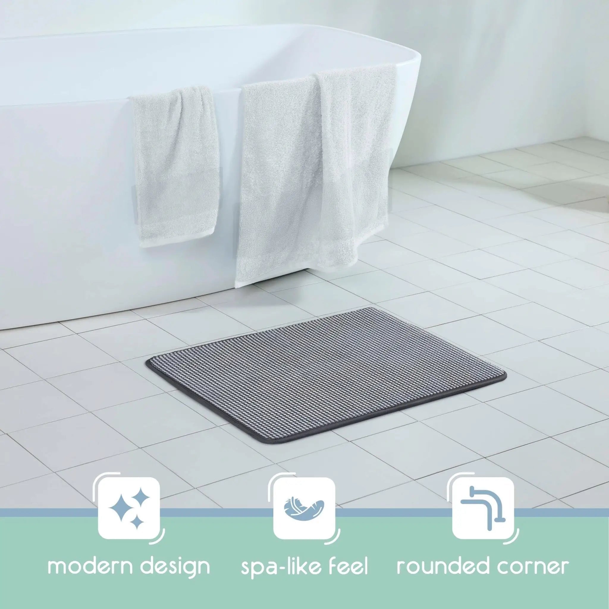 A black bath rug with rounded corners placed on a white tiled bathroom floor. Three feature icons at the bottom read 'modern design', 'spa-like feel', and 'rounded corner'.