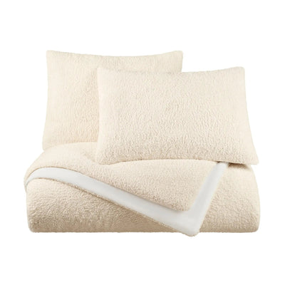 A folded cream-colored plush bedding set, including a textured comforter and two matching pillowcases, displayed on a solid white background.