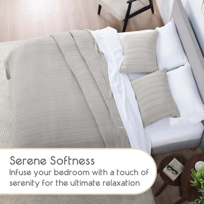 Neatly made bed with gray blanket and pillows in a bedroom setting.