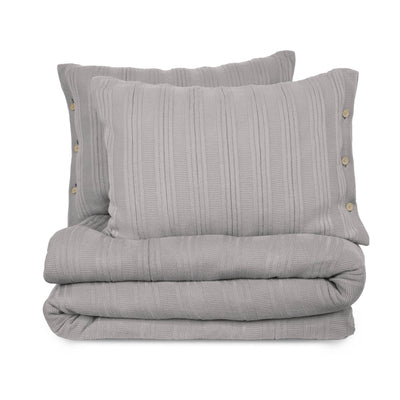 Folded gray textured blanket with two matching pillows on a white background