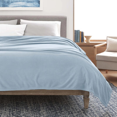 Bed with light blue blanket in a bedroom setting
