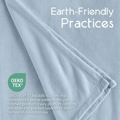 A close-up of a light blue textured fabric with folded edges and white text reading 'Earth-Friendly Practices,' plus a green circular 'Oeko-TEX' badge and smaller text about textile safety.