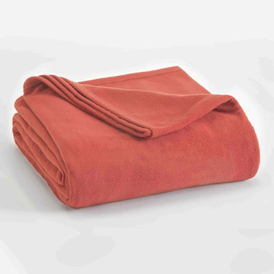 A folded terracotta-colored fleece blanket on a white background.