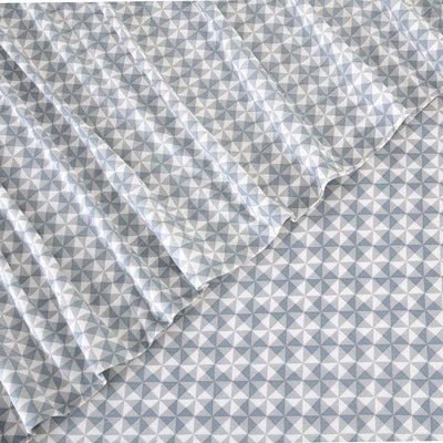 A close-up of a white fabric with a repeating geometric triangle pattern in light blue, shown with soft folds.