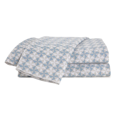 A folded set of cotton bedding, including a duvet cover and matching pillowcases, featuring a geometric star pattern in light blue and white.