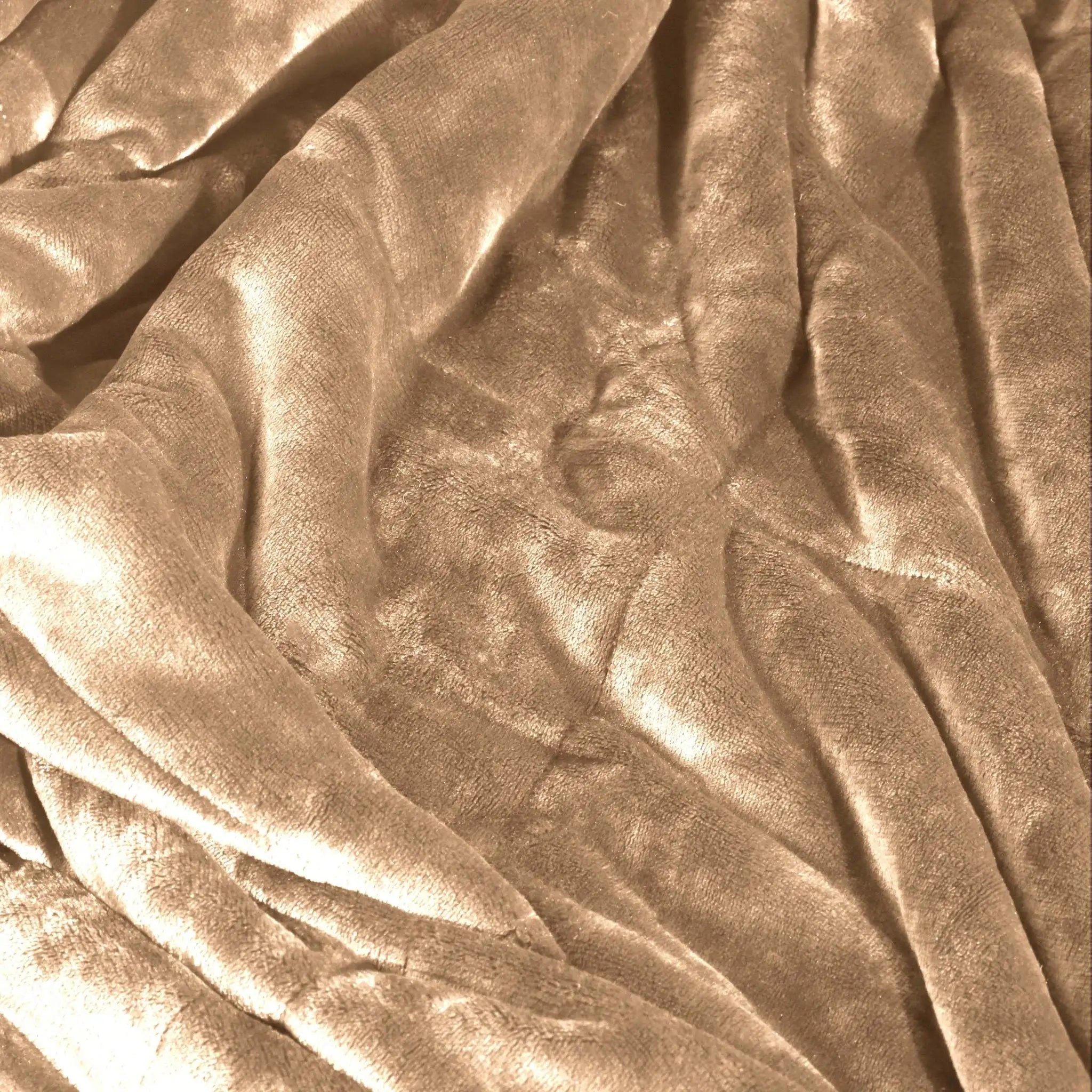 A close-up of draped sand color blanket showing soft folds and a plush texture.