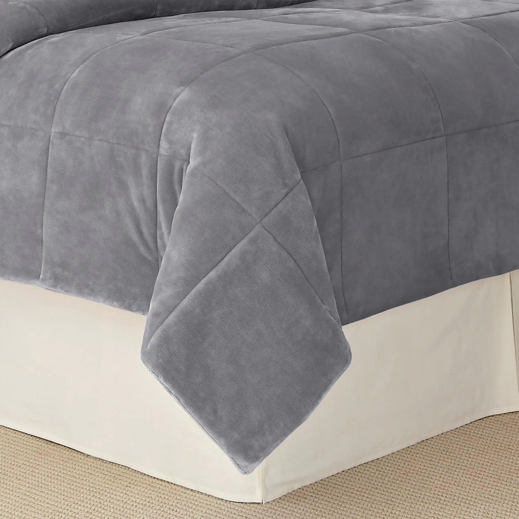 A gray plush quilted blanket draped over a bed.