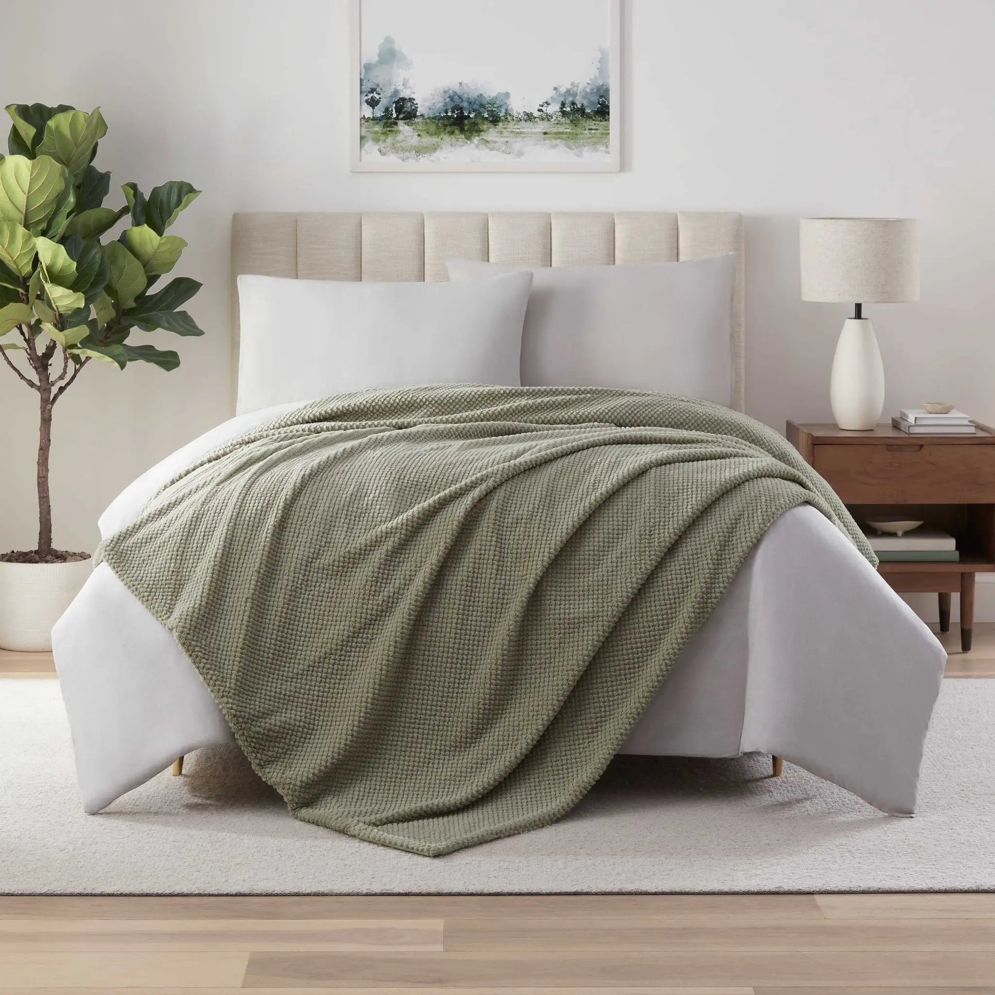 Green blanket on a bed in a bedroom setting.