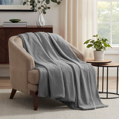 Gray blanket draped over a beige armchair in a living room 