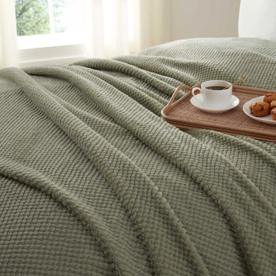 Green blanket draped over a bed.