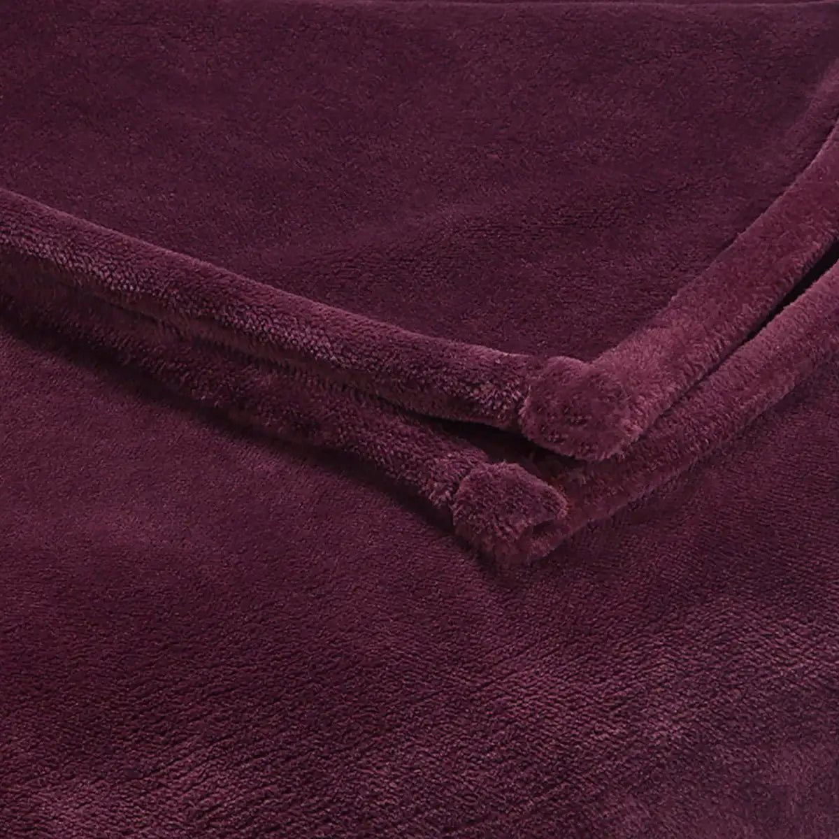 A close-up of a plush, soft-textured blanket in a deep fig color, folded to show its thick, velour-like fabric texture.