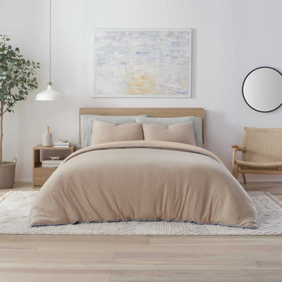 Neatly made bed with beige bedding in a modern bedroom setting.