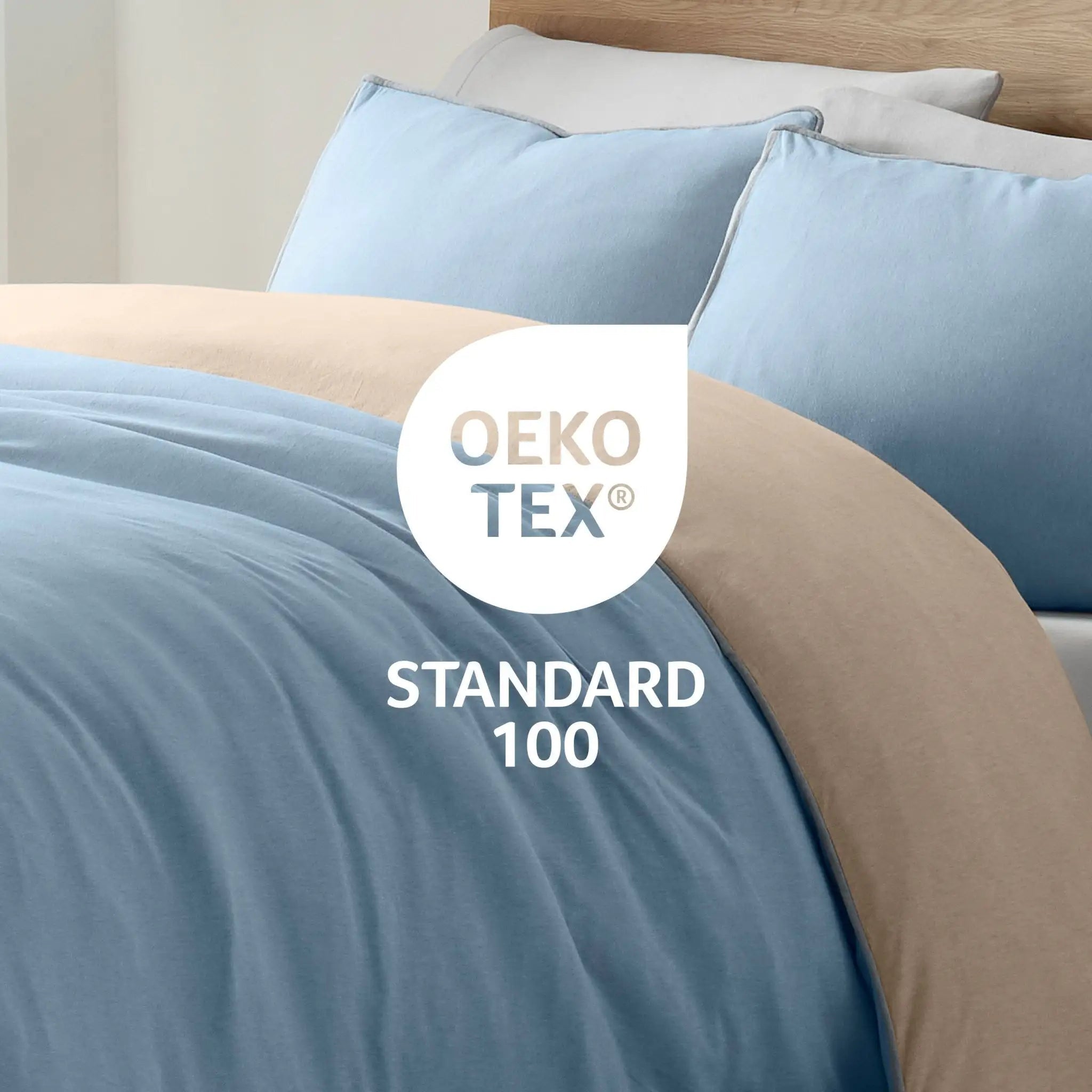 Bed with blue and beige bedding and Oeko-Tex Standard 100 logo.