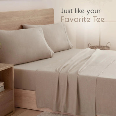 Beige bed sheets on a bed with pillows and wooden headboard, text 'Just like your Favorite Tee'.