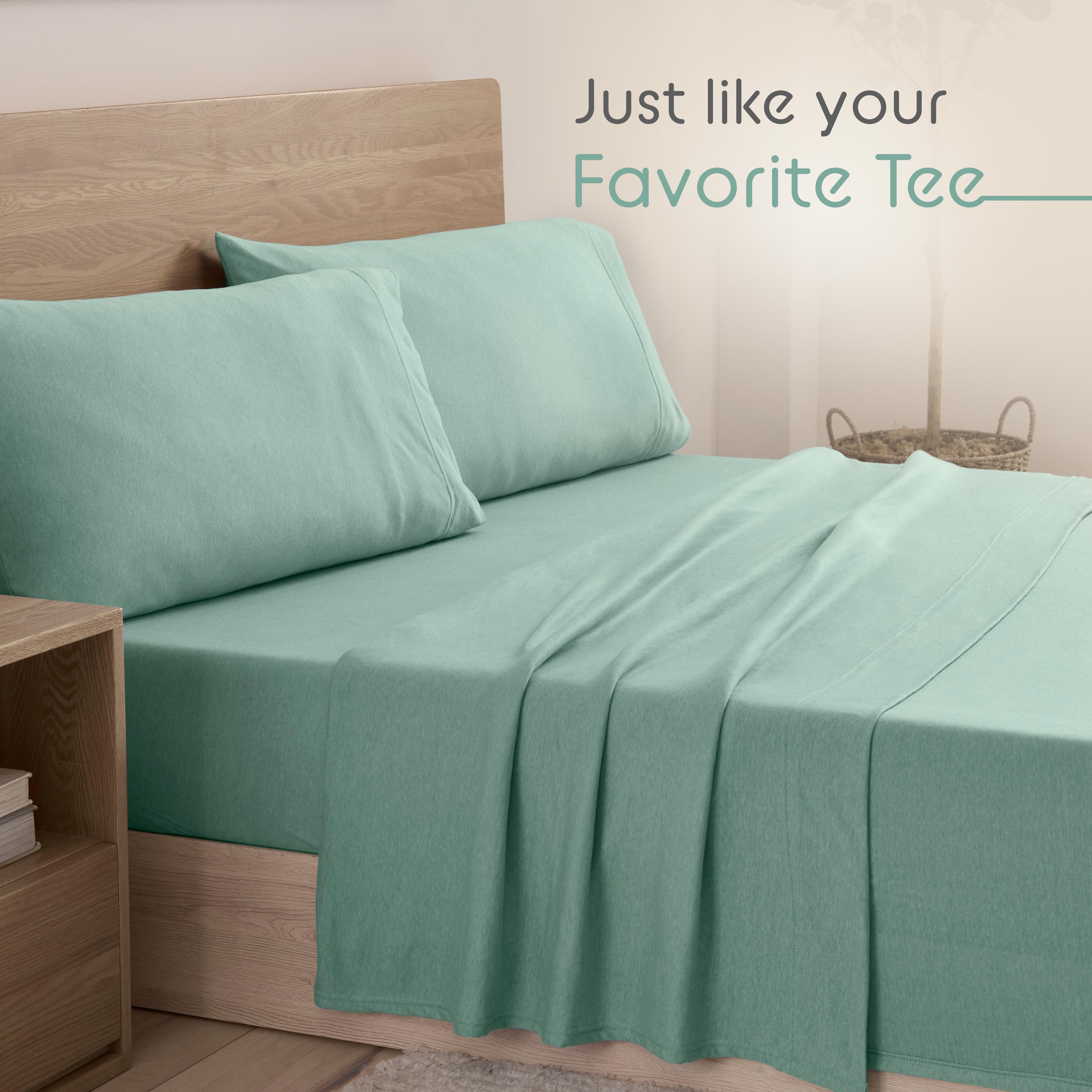 Light teal bed sheets and pillowcases neatly arranged on a wooden bed frame with a bedside table.