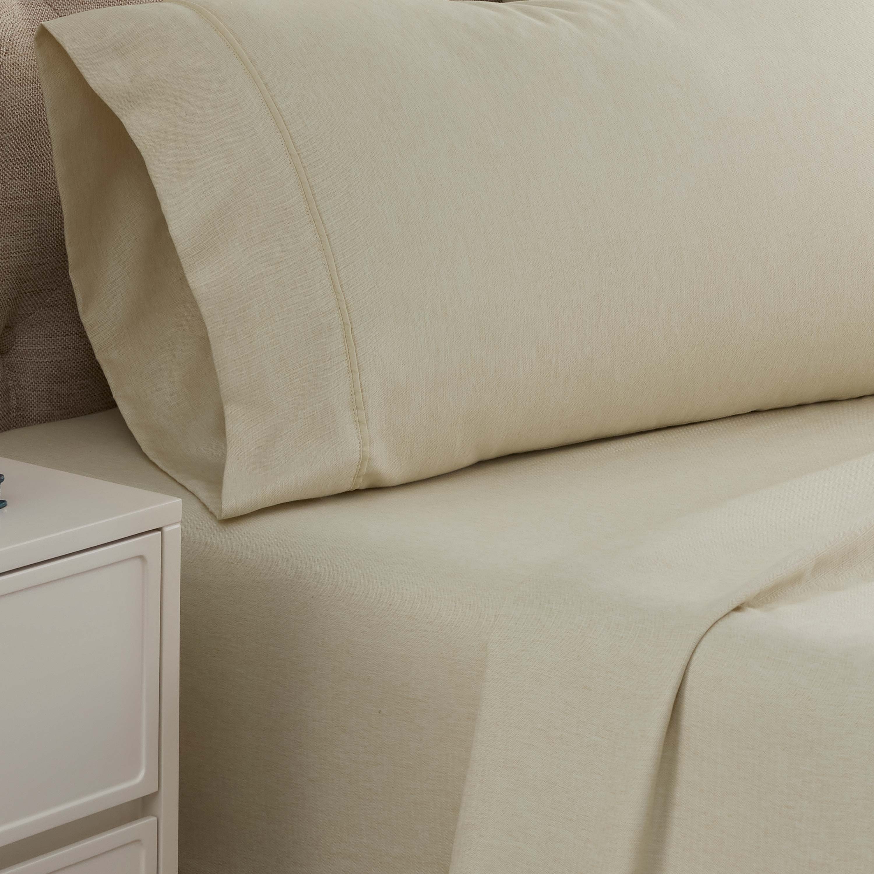 Light beige herringbone sheet set with a matching pillowcase on a bed, next to a nightstand.