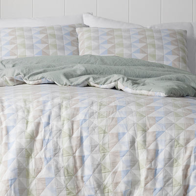 Multi-colored comforter set featuring geometric patterns and coordinating pillow shams on a bed.