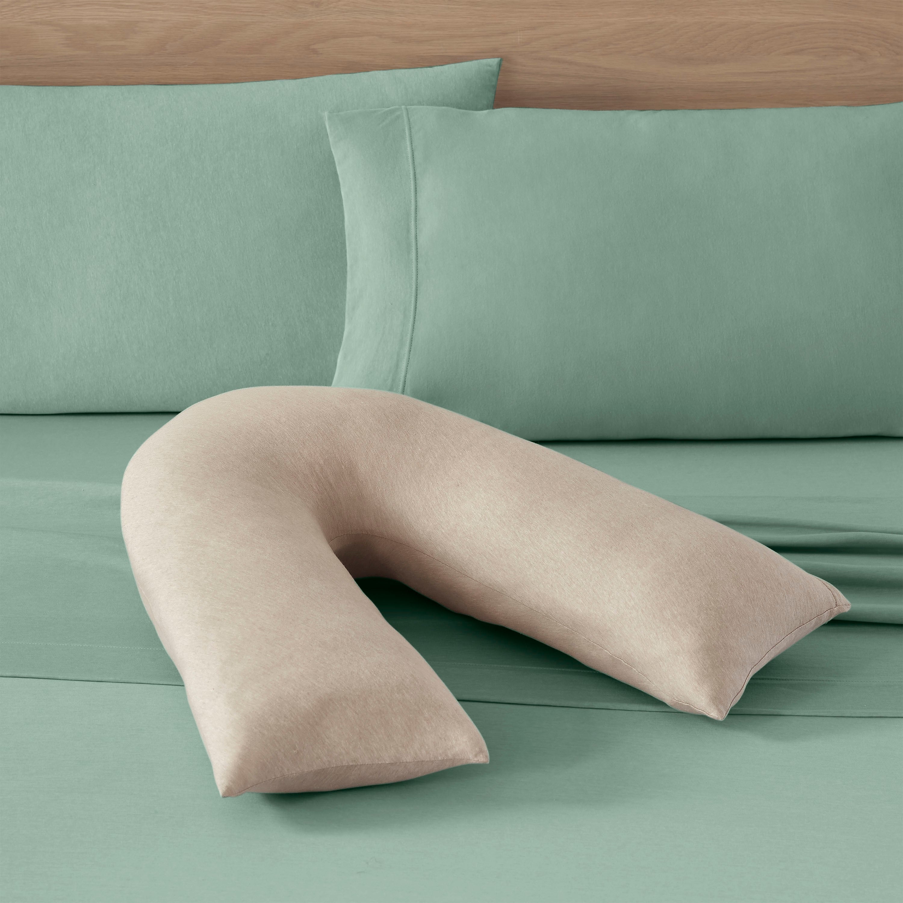 Light green sheet set with matching pillowcases and a beige U-shaped pillow on top.