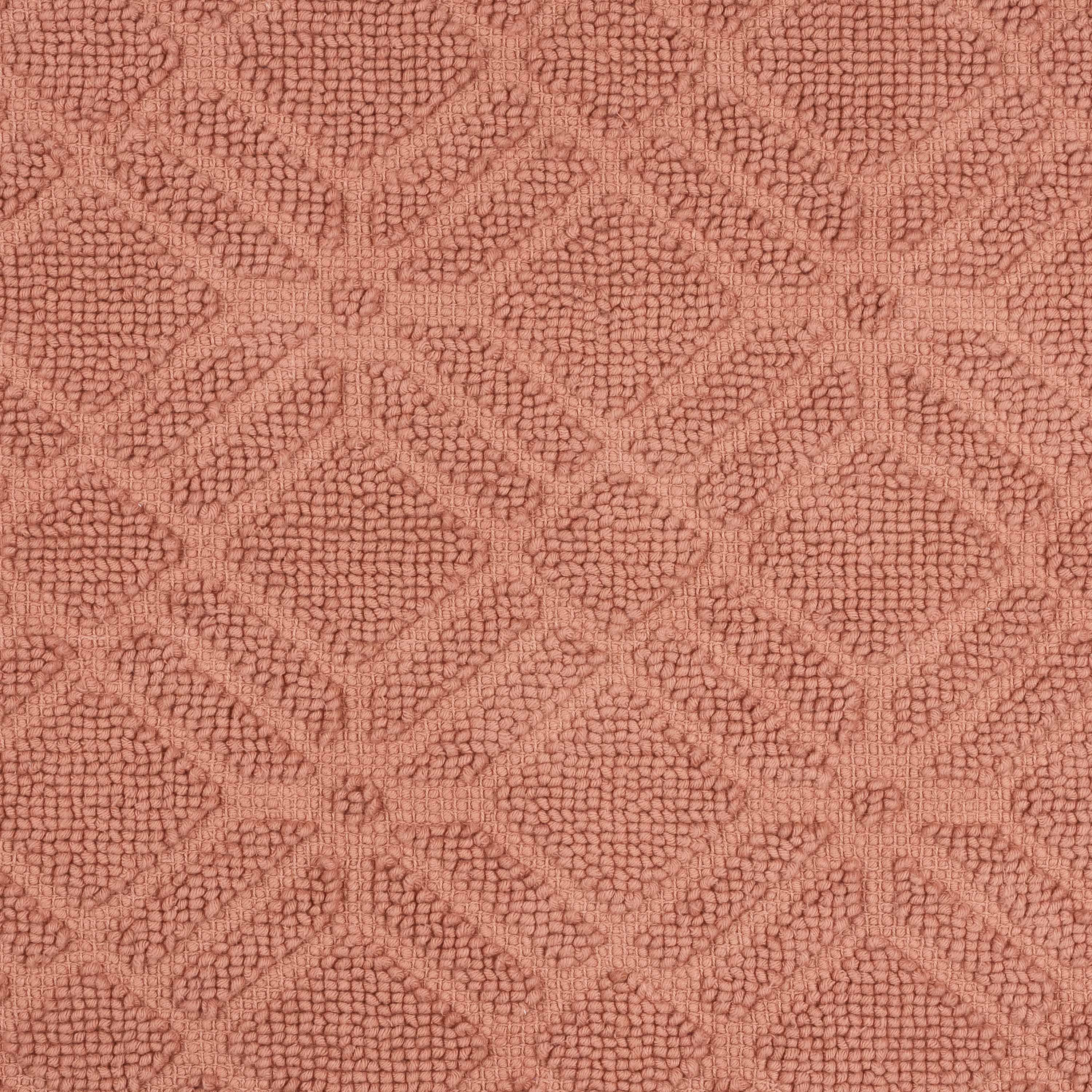 Textured bath rug in a geometric diamond pattern, featuring a soft, muted pink color.