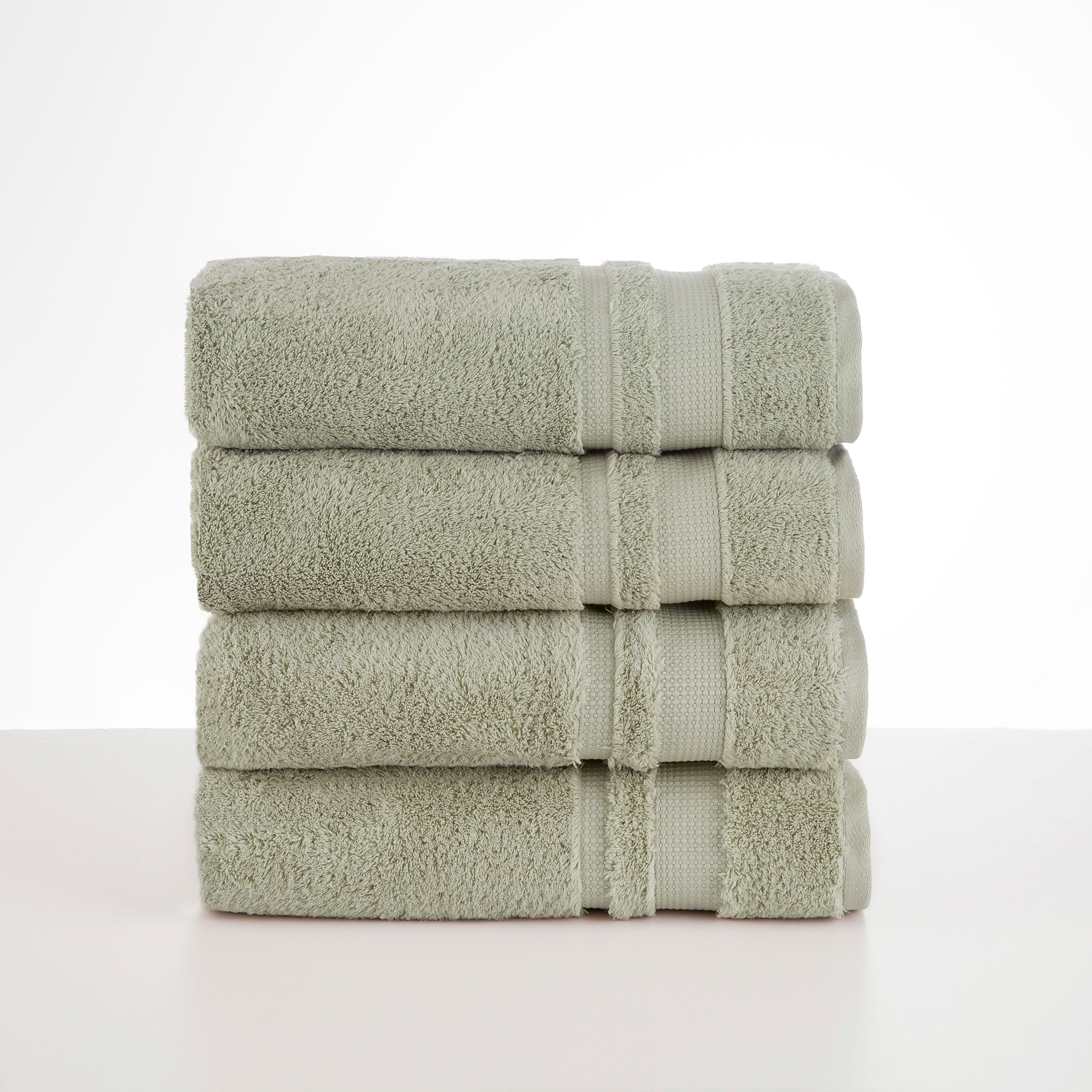 Four stacked soft green towels with textured fabric and decorative bands.